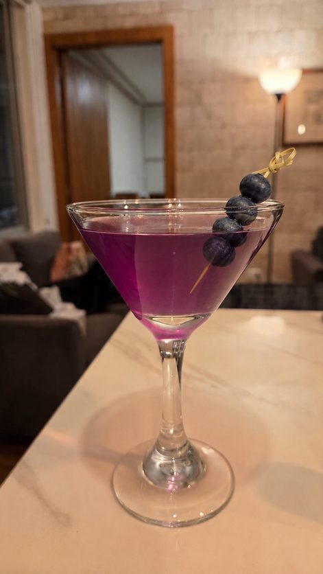Cóctel Lila Aura en copa martini con arándanos